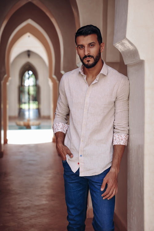 A fish named Fred - Shirt stripe linen - Men’s sand-colored linen shirt with subtle stripes, rolled sleeves revealing pink patterned cuffs, paired with blue jeans,.