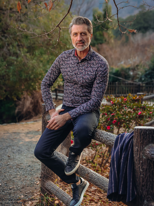 A Fish Named Fred men's Wagasa shirt in Navy, worn by a model leaning on a fence on a woodland path