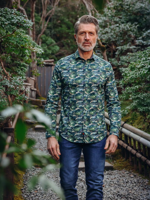 A Fish Named Fred men's Fuji Dream shirt in Dark Green, worn by a model on a garden path