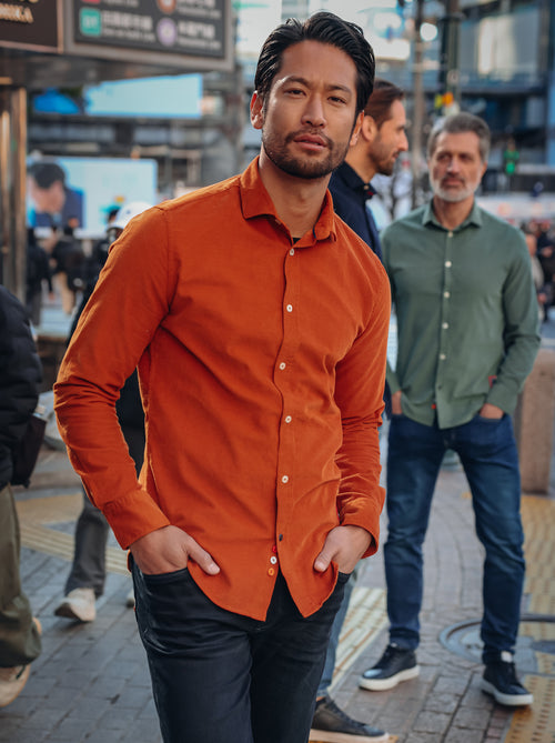 A Fish Named Fred men's Corduroy shirt in Cognac, worn by a model on a busy city street