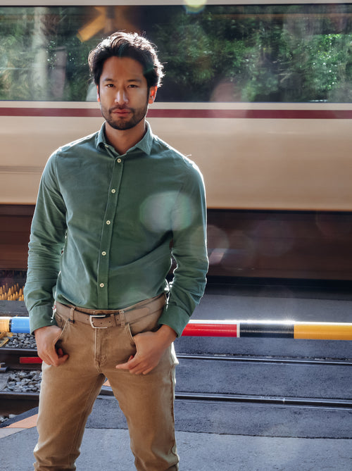 A Fish Named Fred men's Corduroy shirt in Forest Green, worn by a model at a level crossing