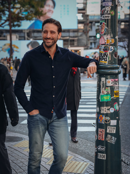 A Fish Named Fred men's Corduroy shirt in Navy, worn by a model leaning on a lamp post in the city