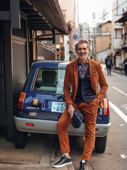 A Fish Named Fred men's Rib blazer in Cognac, worn by a model leaning on a car bonnet, Tokyo Trip campaign