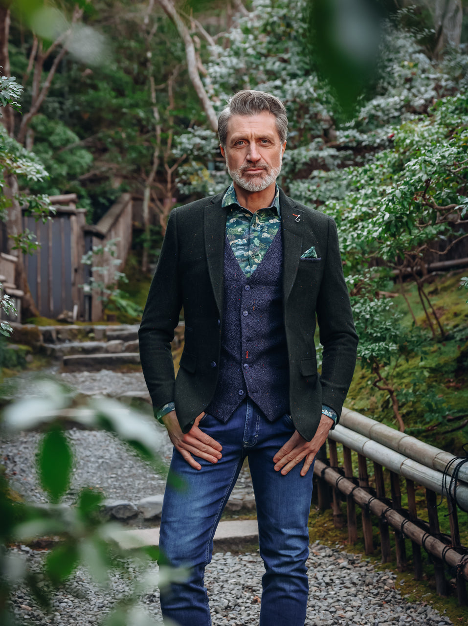 A Fish Named Fred men's Herringbone blazer in Dark Green, worn by a model on a garden path
