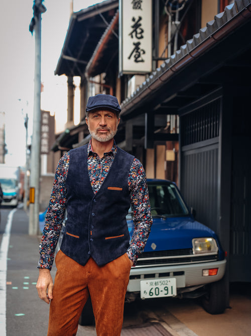 A Fish Named Fred men's Rib waistcoat in Navy, worn by a model on a quiet street beside a blue car, AW26 campaign