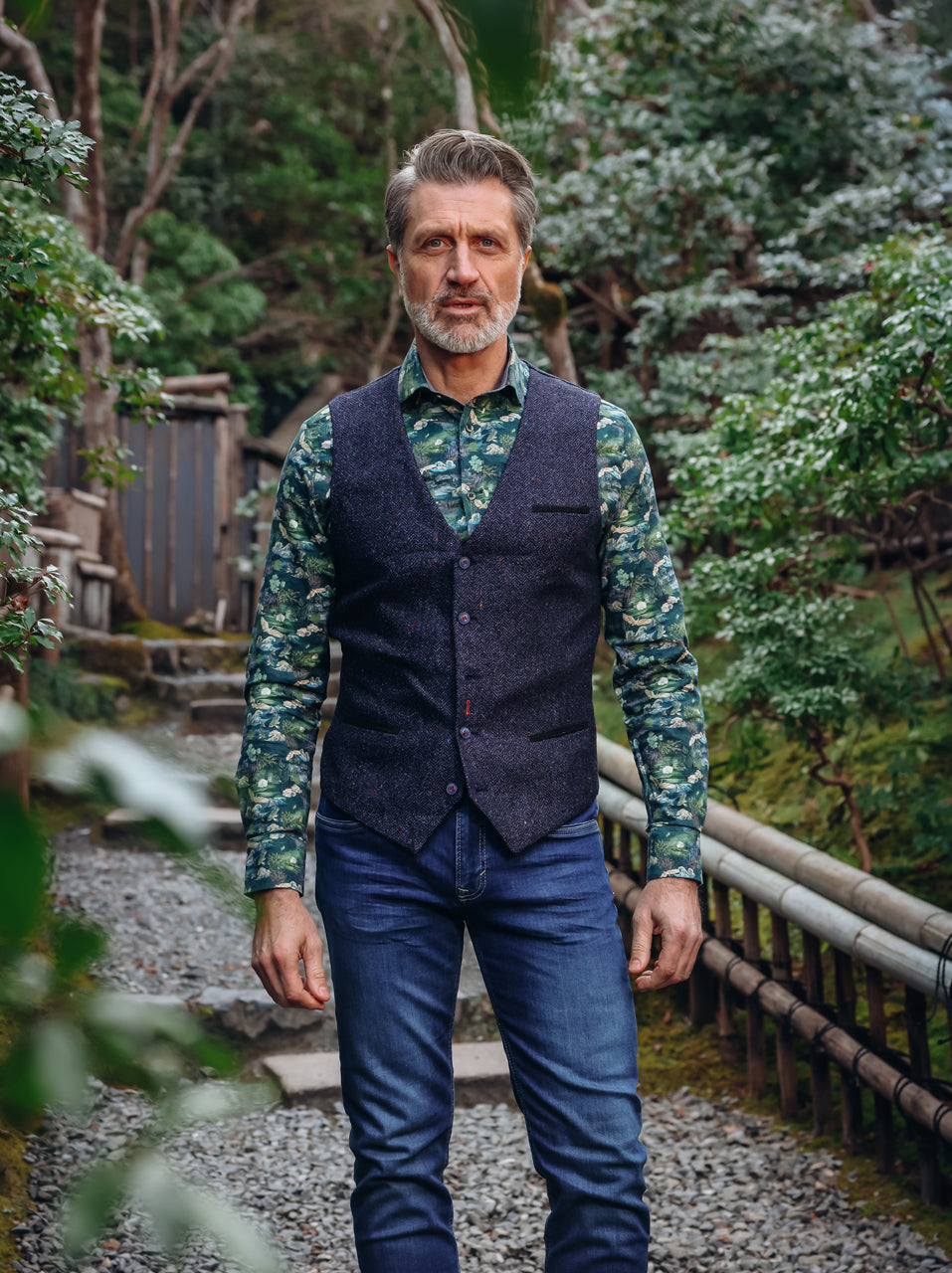 A Fish Named Fred men's Herringbone waistcoat in Navy, worn by a model on a garden path, AW26 campaign