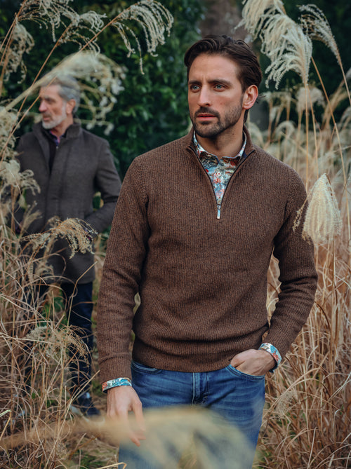 A Fish Named Fred men's Mock-zip pullover in Chocolate Brown, worn by a model in tall pampas grass, AW26 campaign