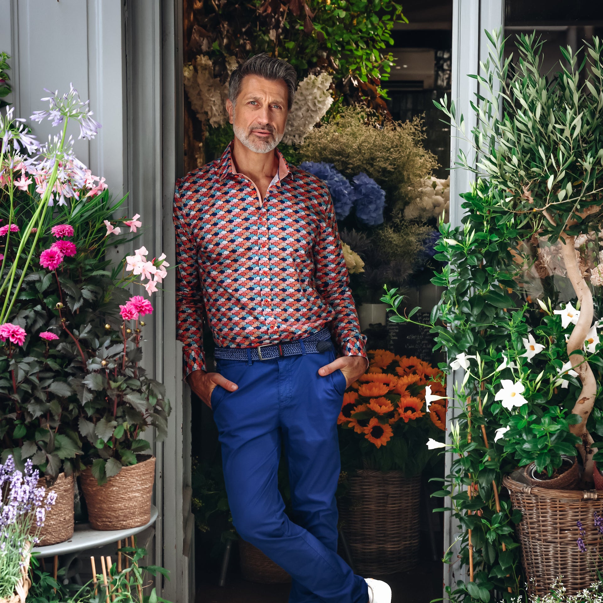 Man standing in a doorway surrounded by plants and flowers