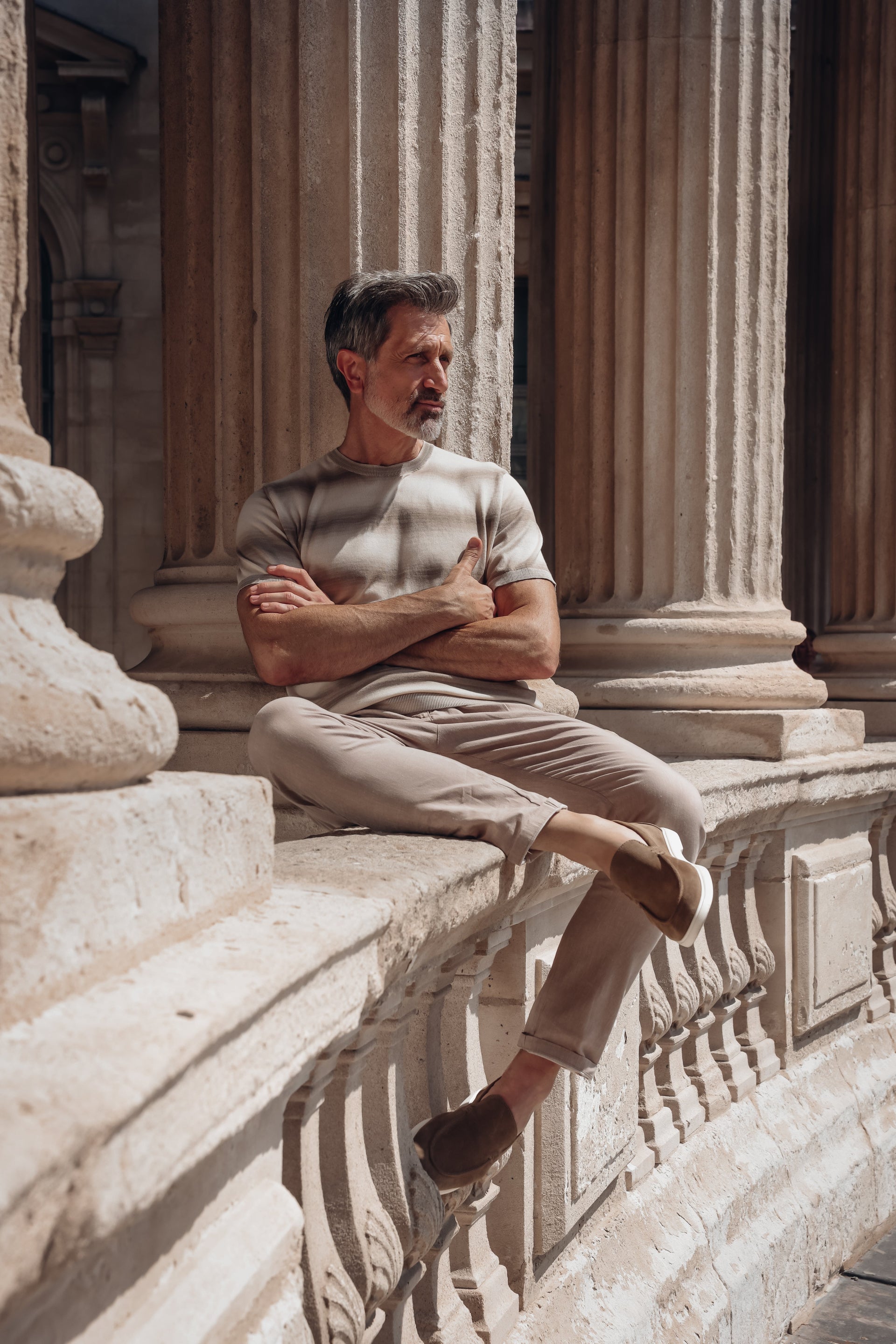 Man sitting on stone steps with classical architecture in the background