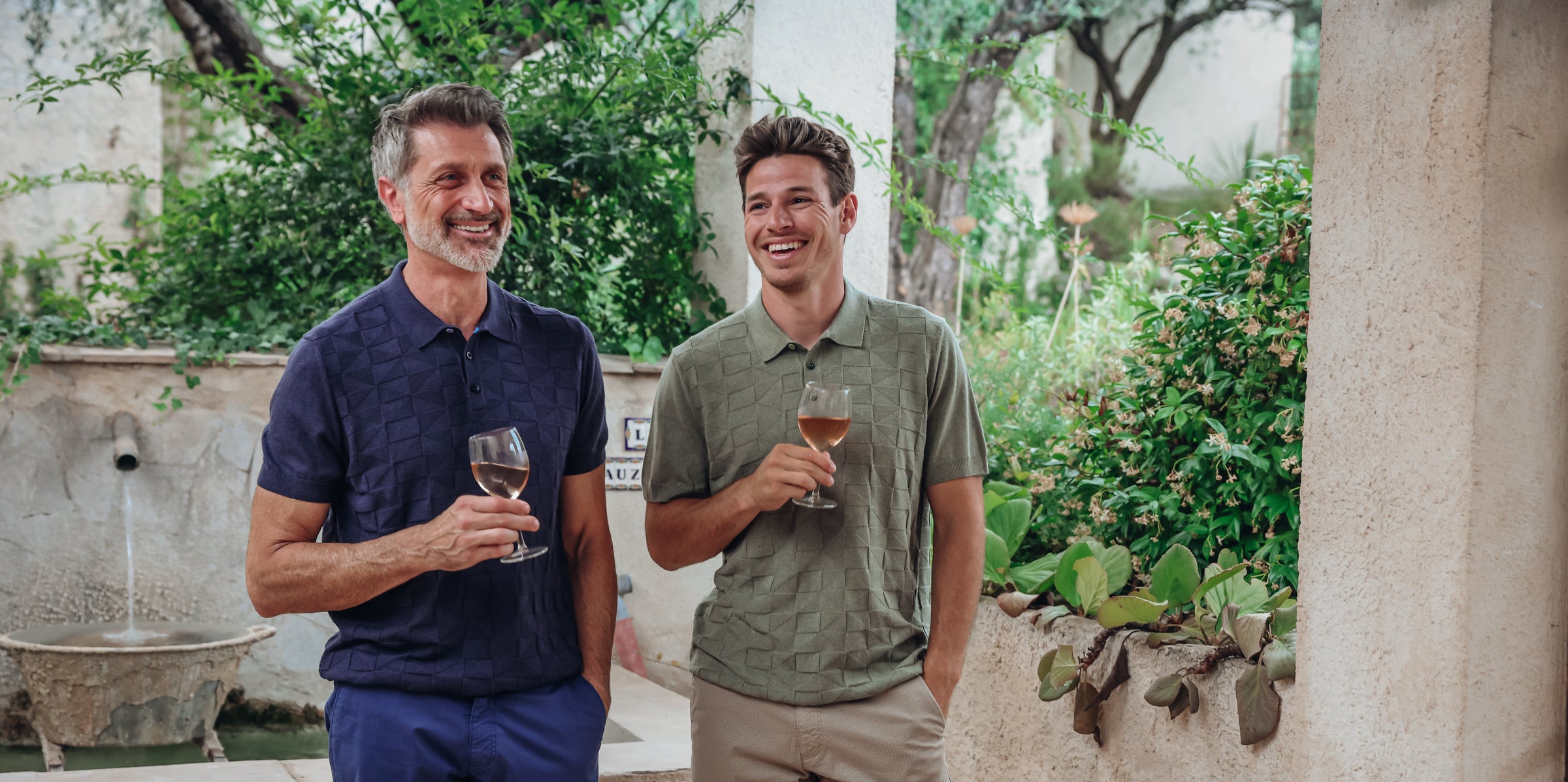 Two men holding wine glasses in a garden setting