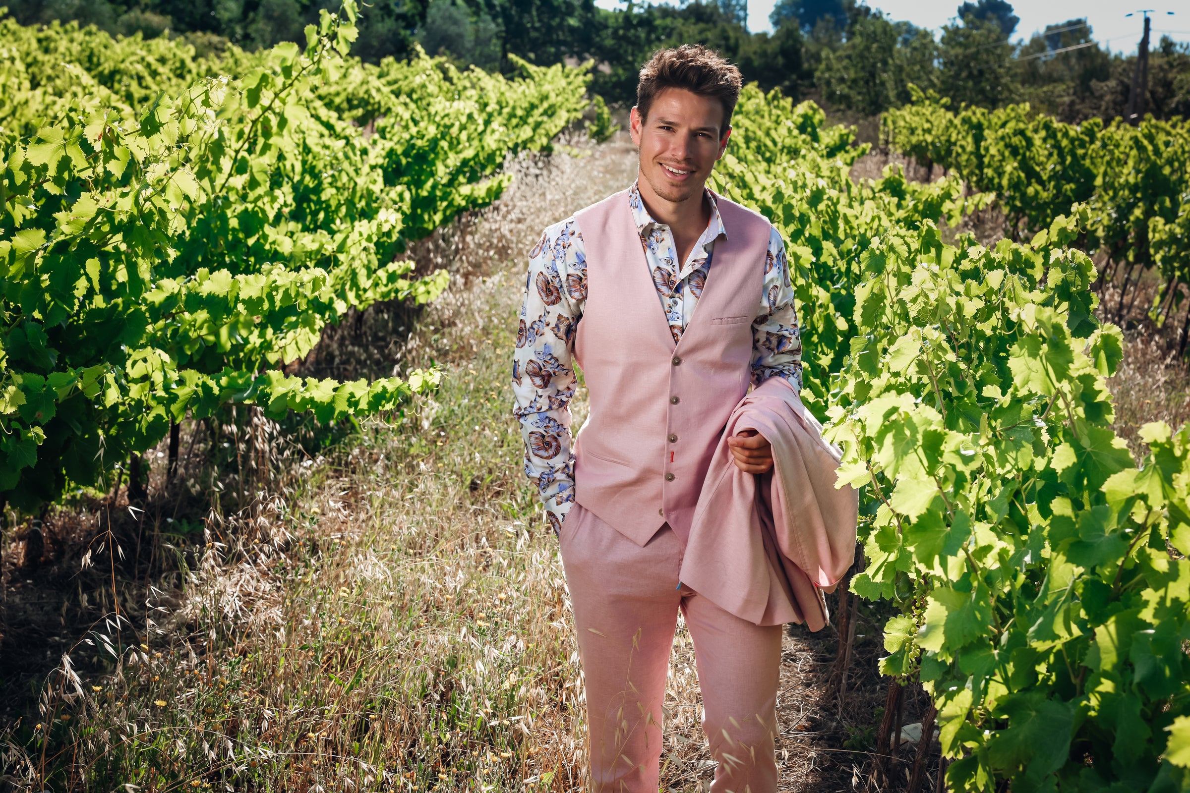 Man in a pink suit standing in a vineyard
