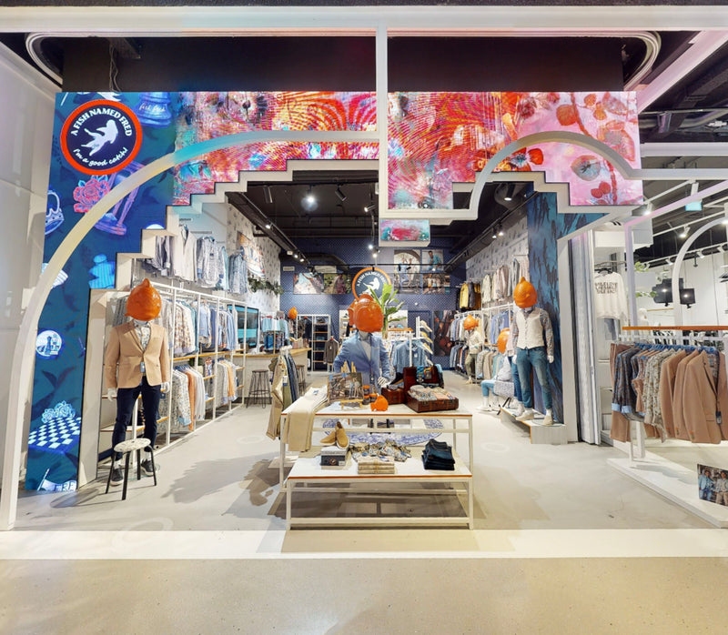 Interior of a clothing store with colorful walls and various clothing items on display.